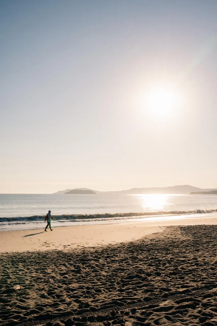 Pessoa caminhando na areia de uma praia de mar aberto em Florianópolis
